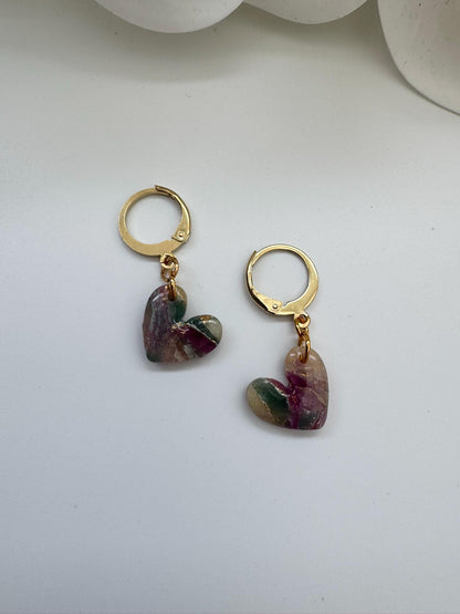 Gold hoop earrings with heart-shaped gemstones on a white background