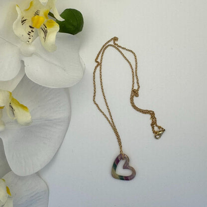 Necklace with a heart-shaped pendant on a white surface with flowers.
