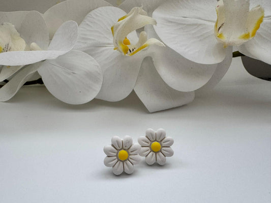 White daisy earrings with yellow centers on a white background