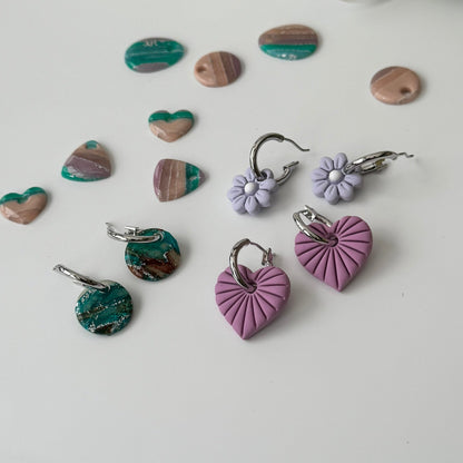 Heart-shaped earrings in various colors on a light background