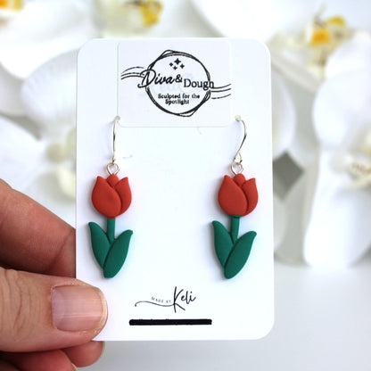 orange tulip-shaped earrings on a 'Diva & Dough' branded card held by a hand.