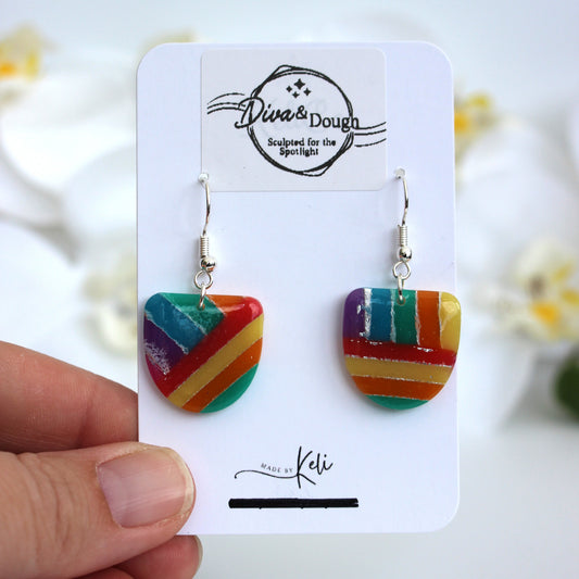 Colorful striped earrings on a 'Diva & Dough' branded card held by a hand.
