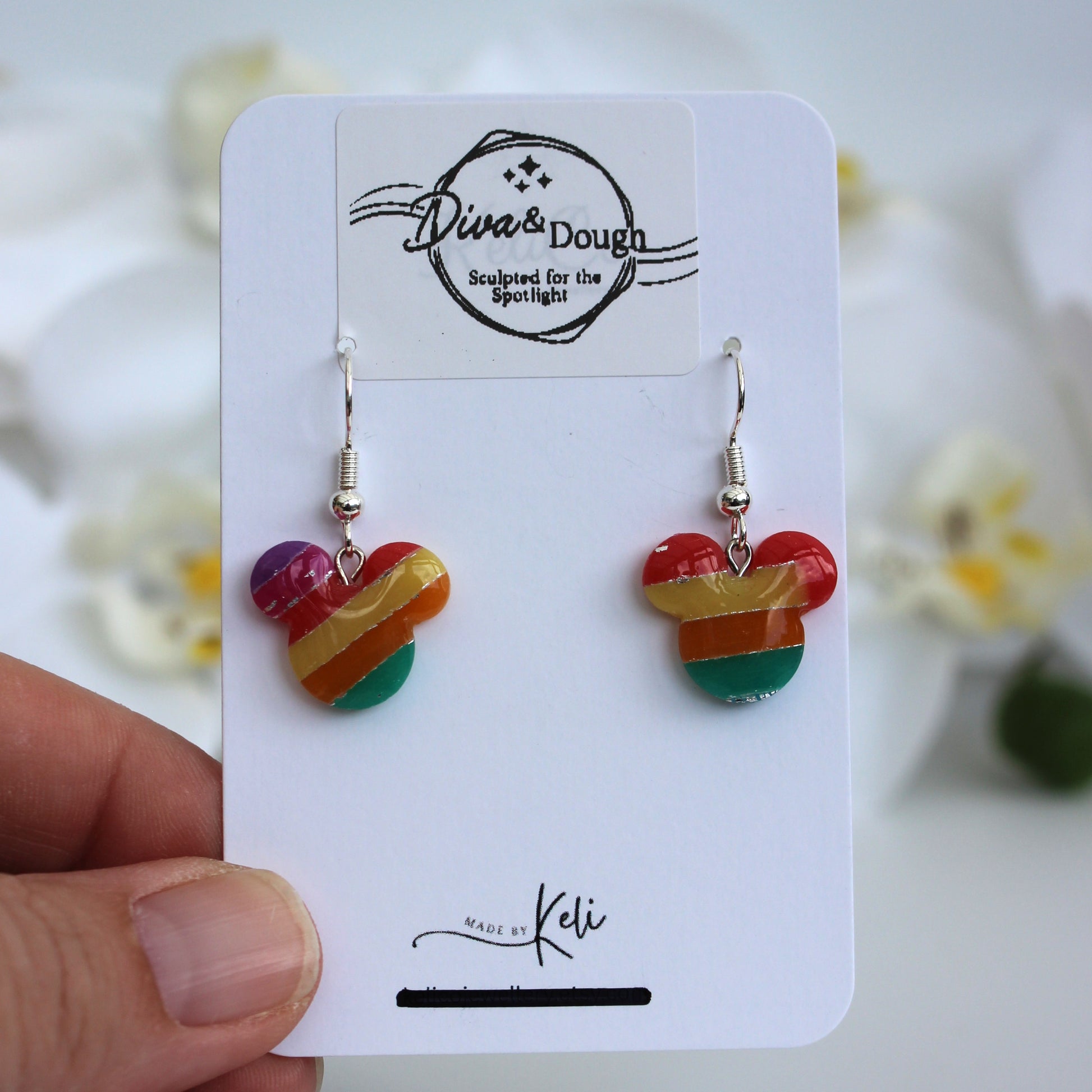 Colorful heart-shaped earrings on a 'Diva & Dough' branded card held by a hand.