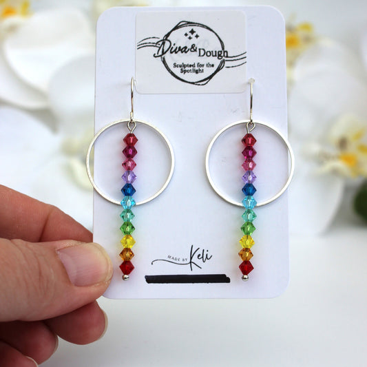 Rainbow beaded earrings on a 'Diva & Dough' branded card held by a hand.