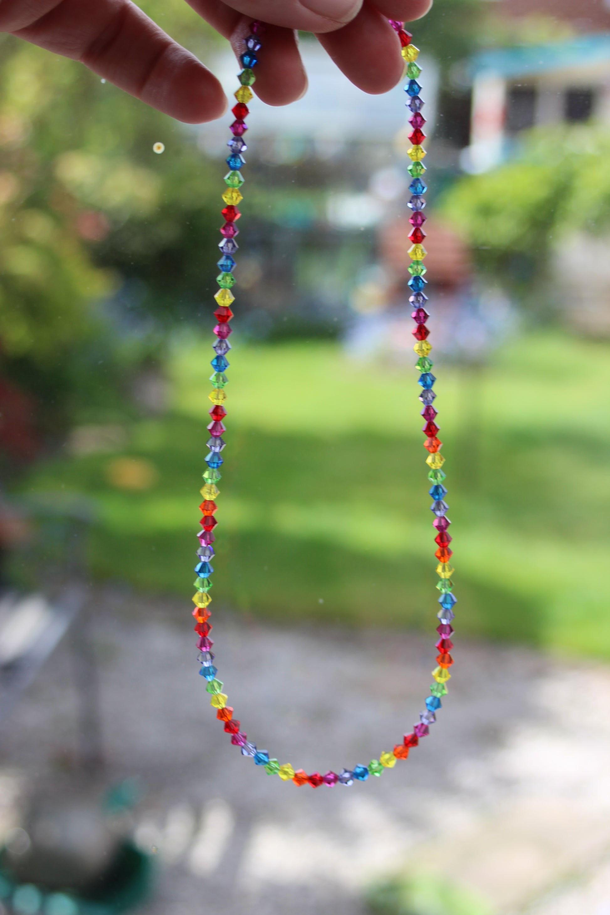 Colorful beaded bracelet held by a hand with a blurred natural background