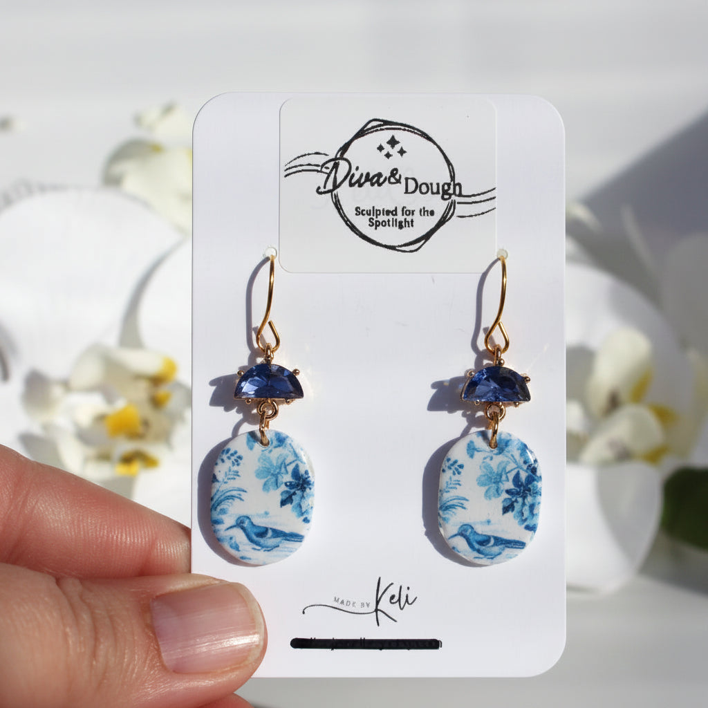 Pair of earrings on a 'Diva & Dough' branded card with floral and blue accents.