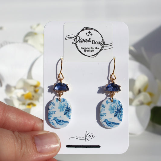 Pair of earrings on a 'Diva & Dough' branded card with floral and blue accents.