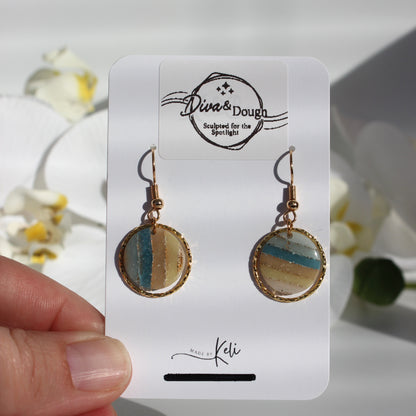 Pair of earrings on a branded card held by a hand with a floral background