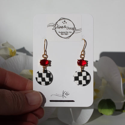 Pair of earrings on a 'Diva & Dough' branded card held by a hand with a blurred background.