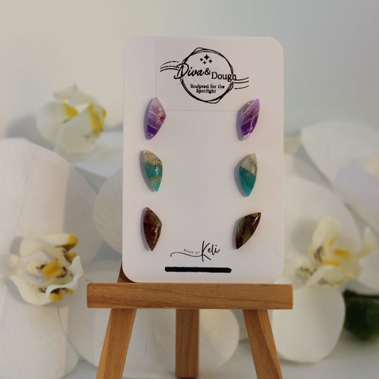 Set of colorful gemstone earrings on a display card with orchids in the background