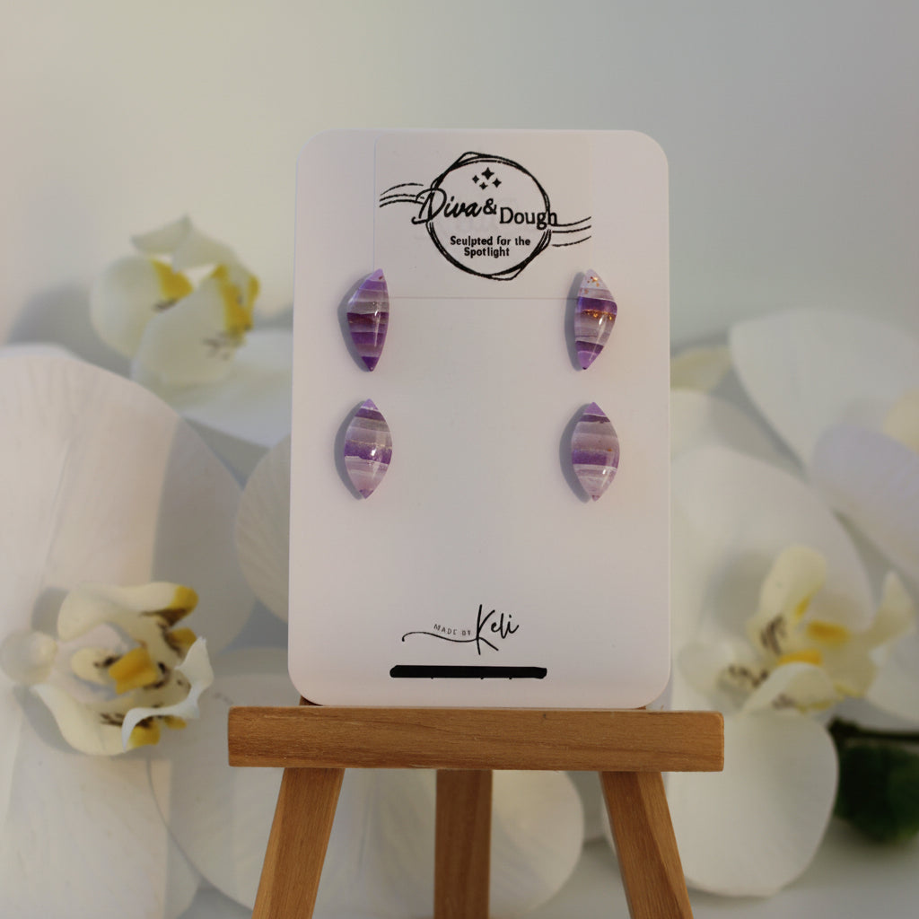 Earring display card with purple earrings on a white background with flowers