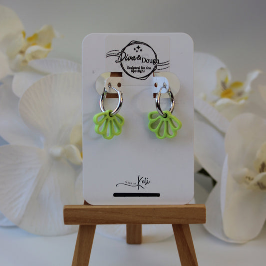 Green floral shaped earrings on a silver hoop on a display card with white orchids in the background