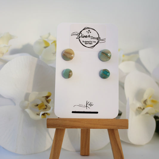 Set of marble effect earrings in green on a display card with a wooden stand, against a light background.