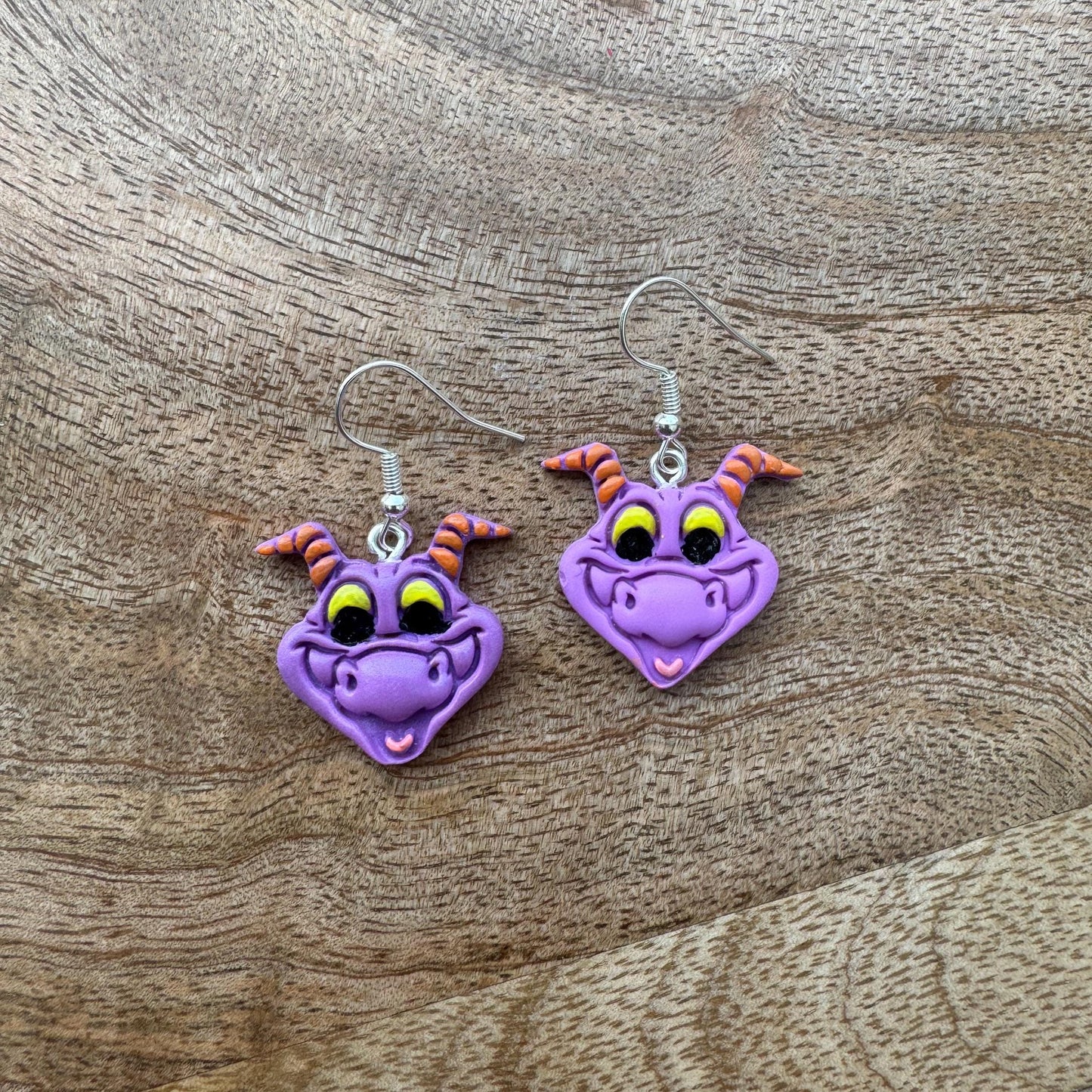 Purple dragon-shaped earrings on a wooden surface