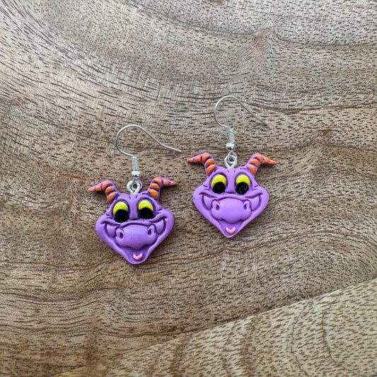 Purple dragon-shaped earrings on a wooden surface