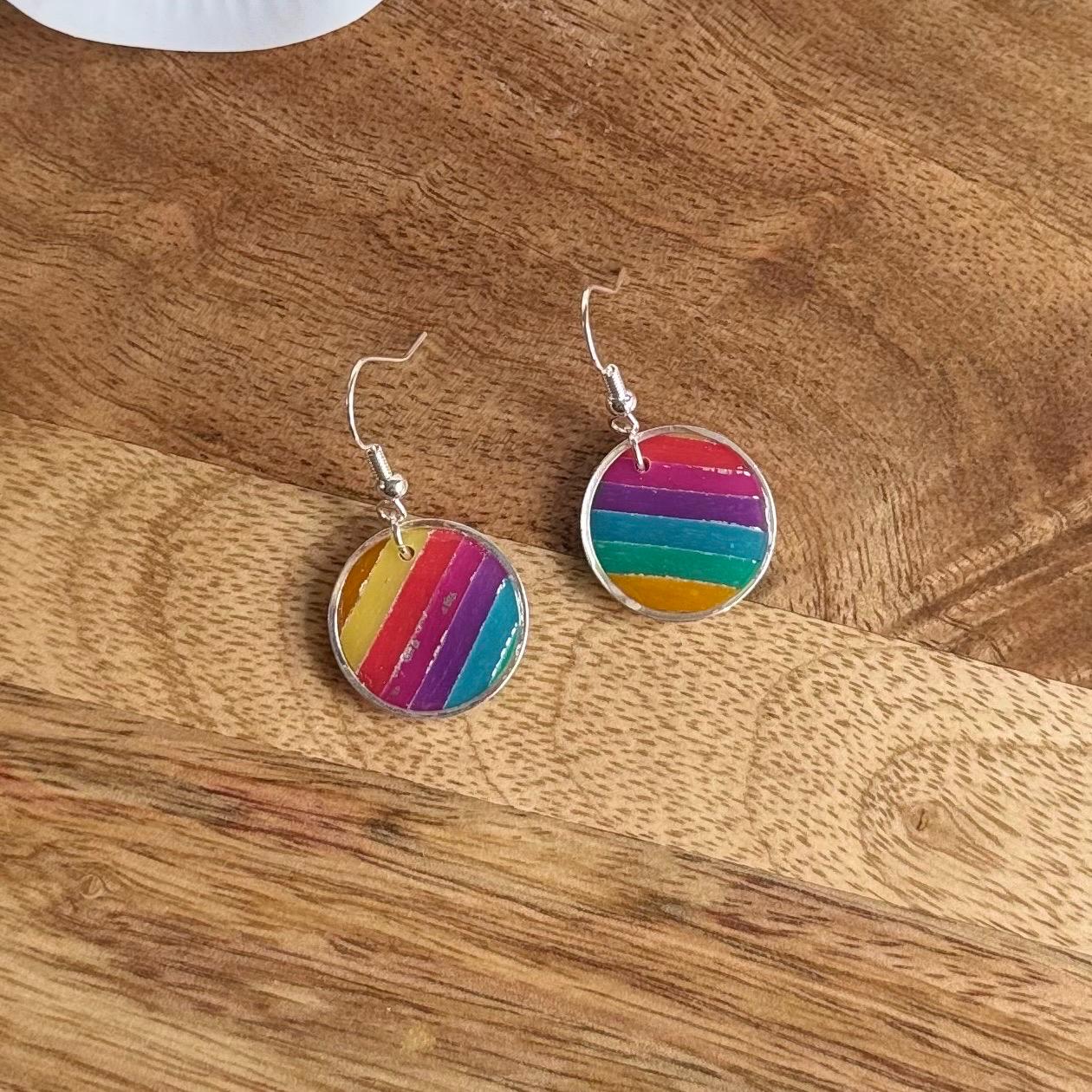 Rainbow striped earrings on a wooden surface