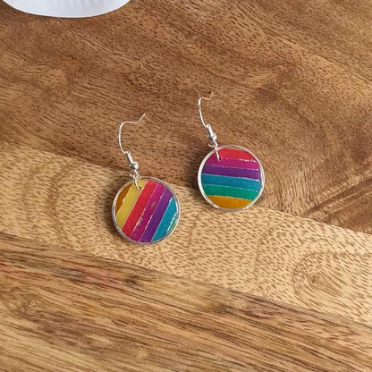 Rainbow striped earrings on a wooden surface
